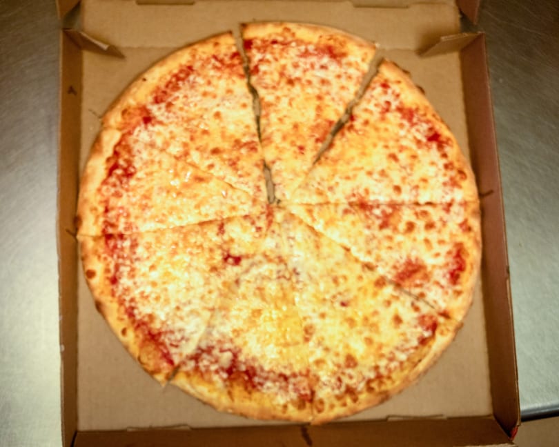 A whole cheese pizza, cut into eight slices, sits inside an open cardboard delivery box.