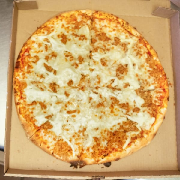 A whole, round pizza with melted cheese and sausage crumbles sits in an open cardboard box.